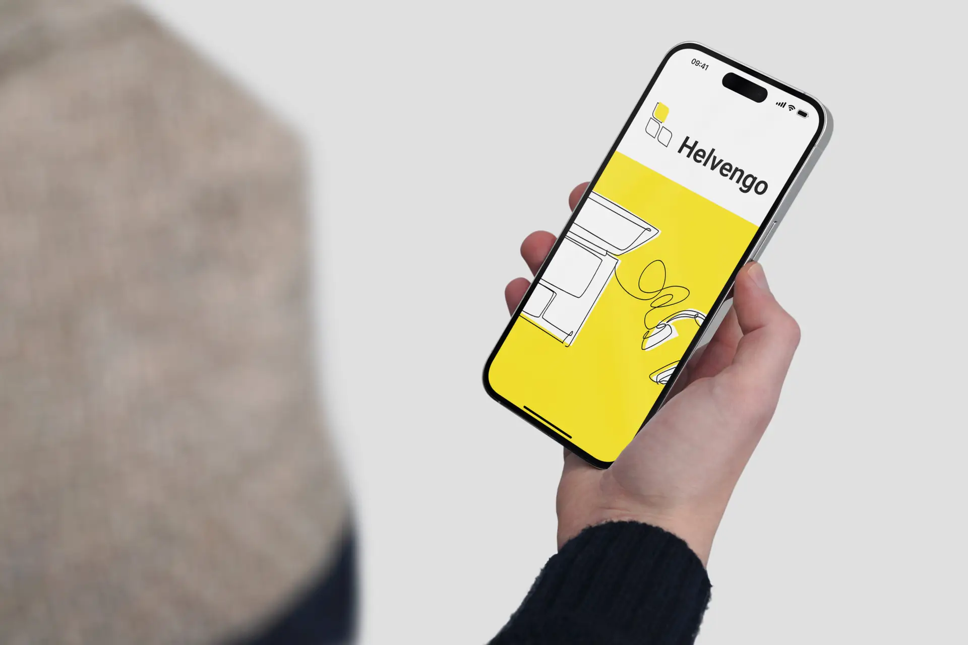 Hand hält Handy, auf dem Handy sieht man den Schriftzug, Logo von Helvengo
